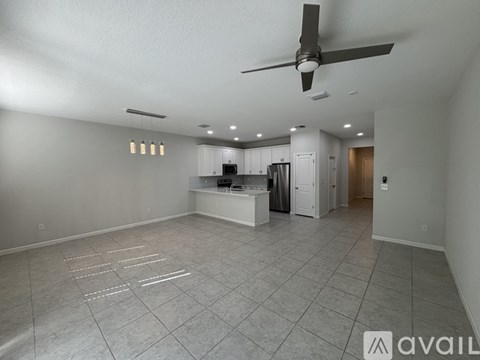 A spacious kitchen and living room with a fan and tiled flooring.