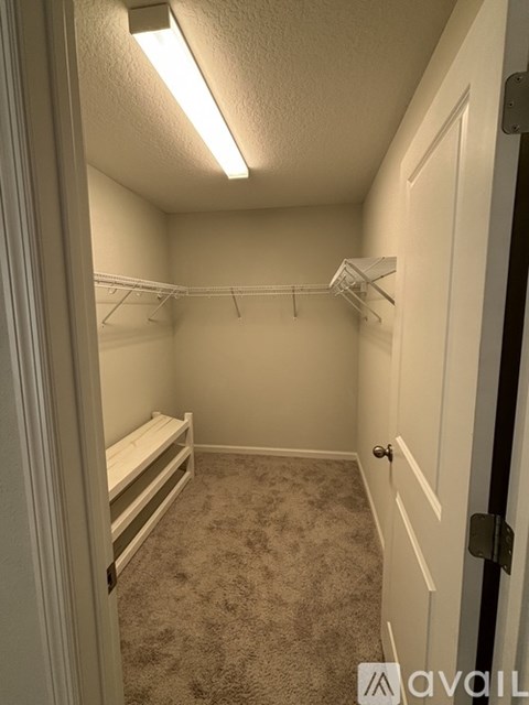 A small, empty bedroom with a carpeted floor and a single bed.