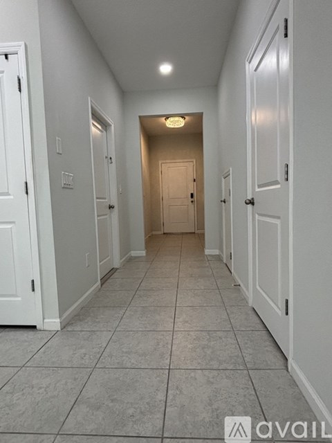 A long hallway with white doors and tiled floors.