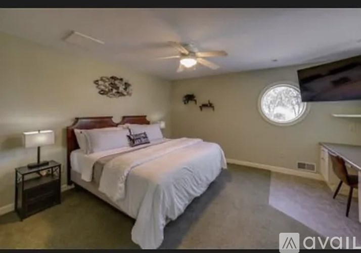 A bedroom with a large bed and a ceiling fan.