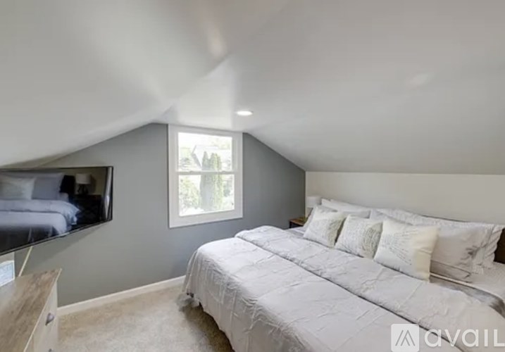 A bedroom with a large bed and a television on the wall.