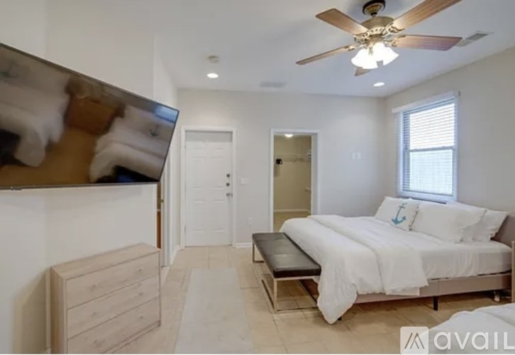 A bedroom with a bed, dresser, and ceiling fan.