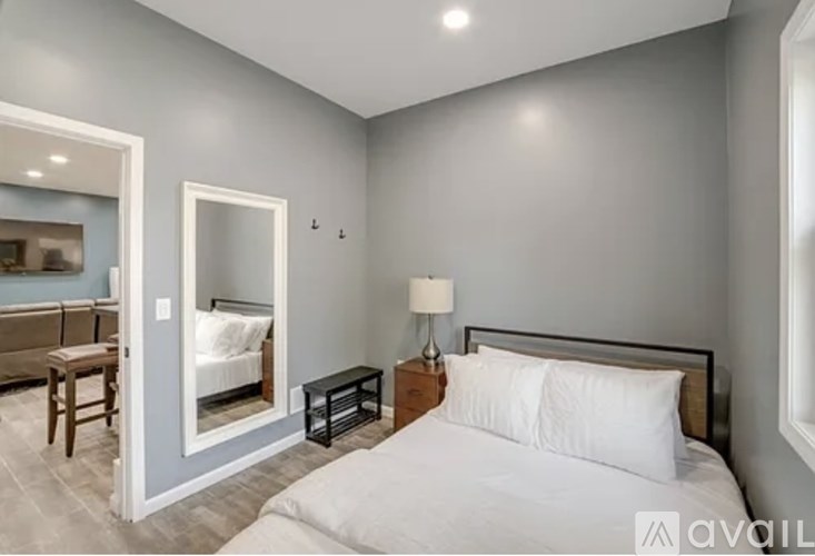 A bedroom with a bed, nightstand, and a mirror.