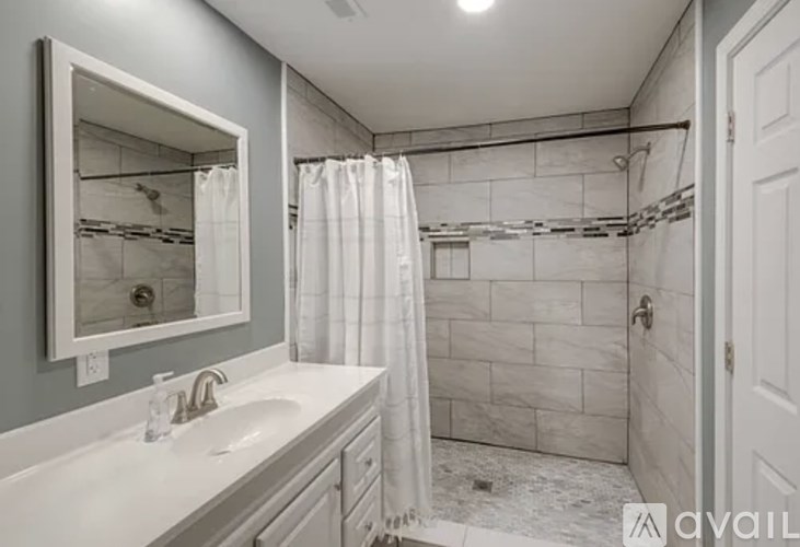 A bathroom with a white sink and a white shower curtain.