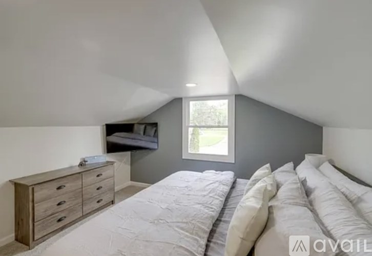 A bedroom with a bed, dresser, and window.