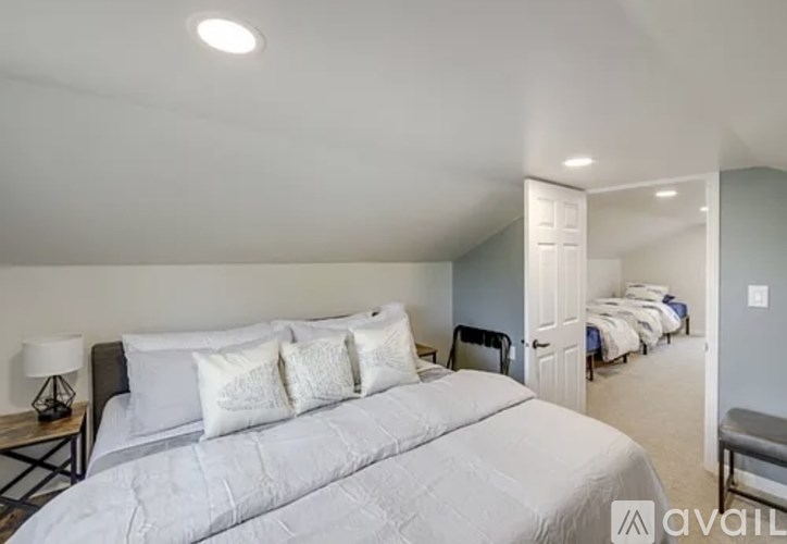 A bedroom with a large bed and a bench in the corner.