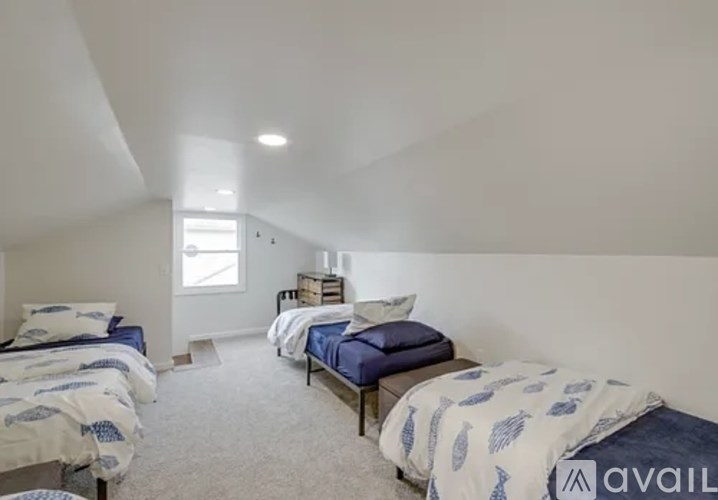 A bedroom with multiple beds and a window.