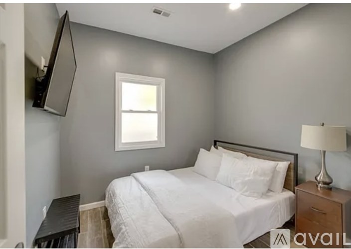 A bedroom with a bed, nightstand, and a window.