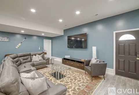 A living room with a grey sofa and a television mounted on the wall.