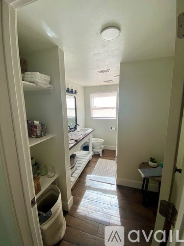 A bathroom with a toilet, sink, and a cabinet with towels and other items.