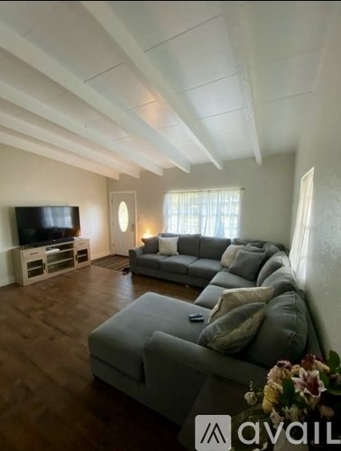 A living room with a grey couch and a television on a stand.