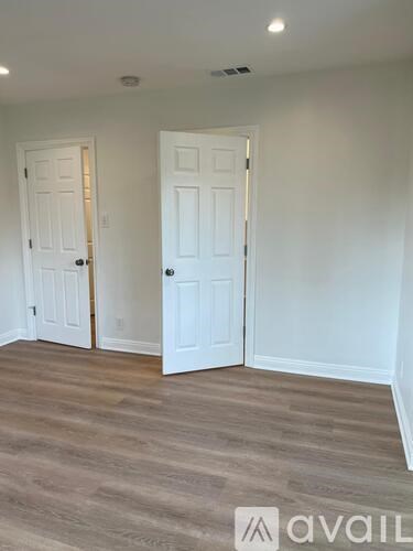 A room with two white doors and wooden flooring.