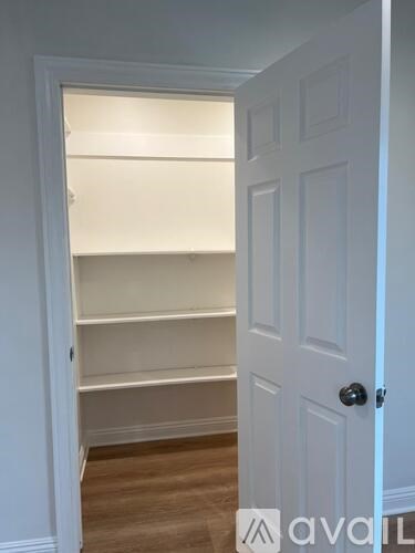 A white door with a black handle is open to a white interior.
