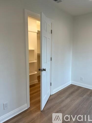 A room with a white door and a wooden floor.