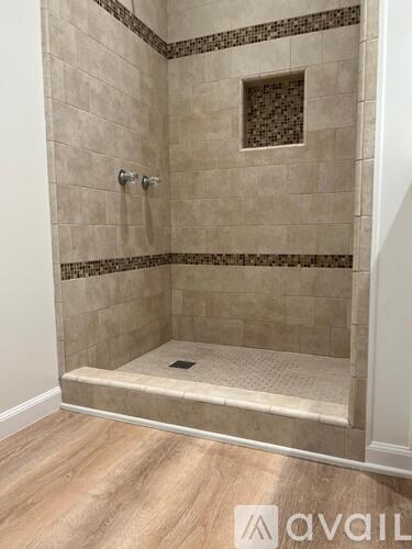A tiled shower with a drain in the middle of the floor.