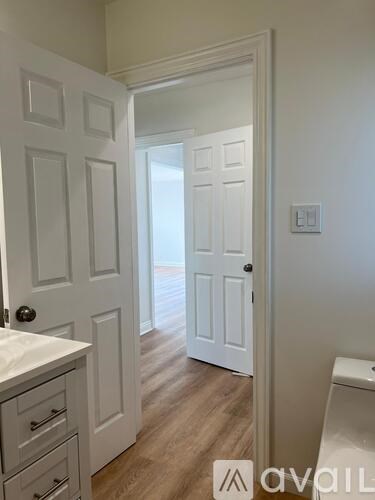 A hallway with a white door and a white cabinet with drawers.