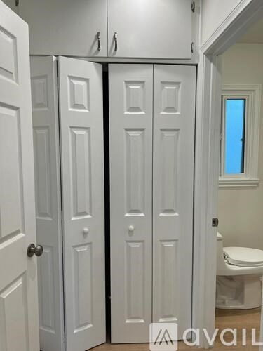 A white bathroom with a toilet and a white door.