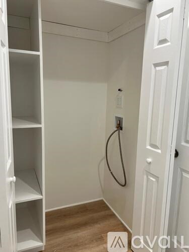 A small white closet with a door and a hose.