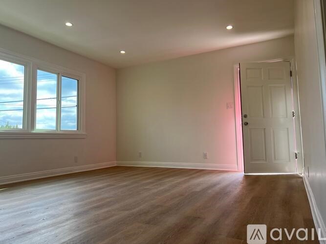 A room with wooden floors and a door leading to another room.