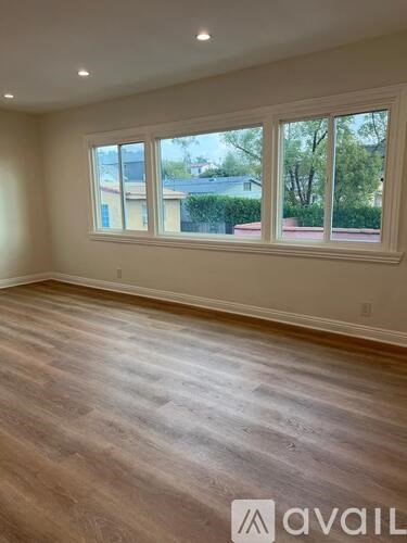 A room with wooden flooring and a large window.