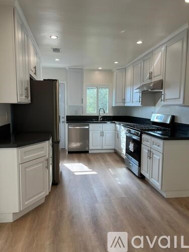 A kitchen with white cabinets and a black countertop.