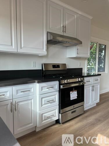 A kitchen with white cabinets and a black stove top.