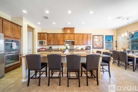 A kitchen with brown cabinets and a center island with chairs around it.