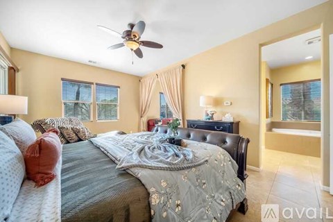 A bedroom with a large bed and a ceiling fan.