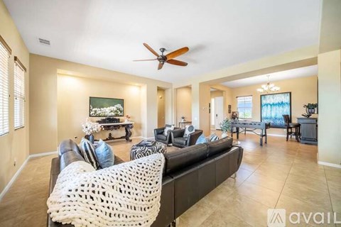 A living room with a black couch and a white knitted chair.