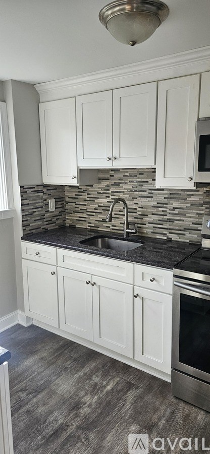A kitchen with white cabinets and a black countertop.