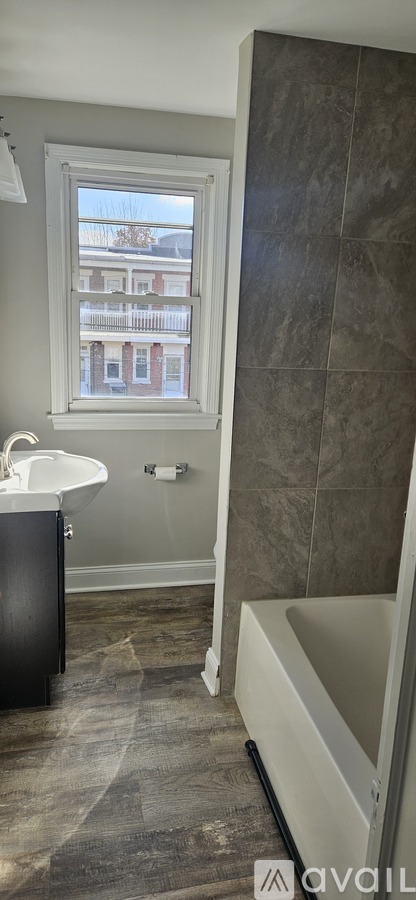 A bathroom with a tub, sink, and window.