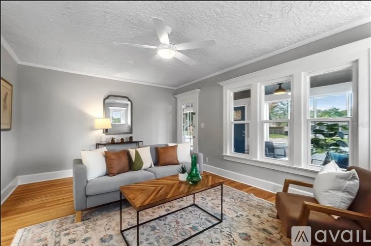 A living room with a grey couch, a wooden coffee table, and a ceiling fan.