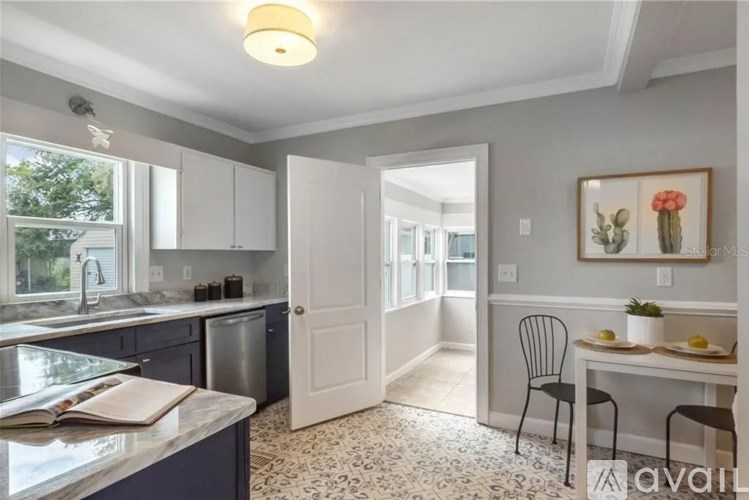 A kitchen with a dining table set up with a chair and a painting on the wall.