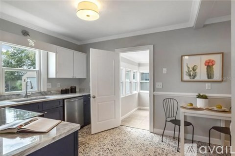 A kitchen with a dining table set up with a chair and a painting on the wall.