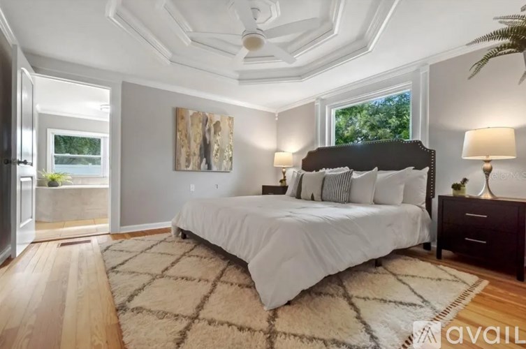 A bedroom with a large bed and a painting on the wall.