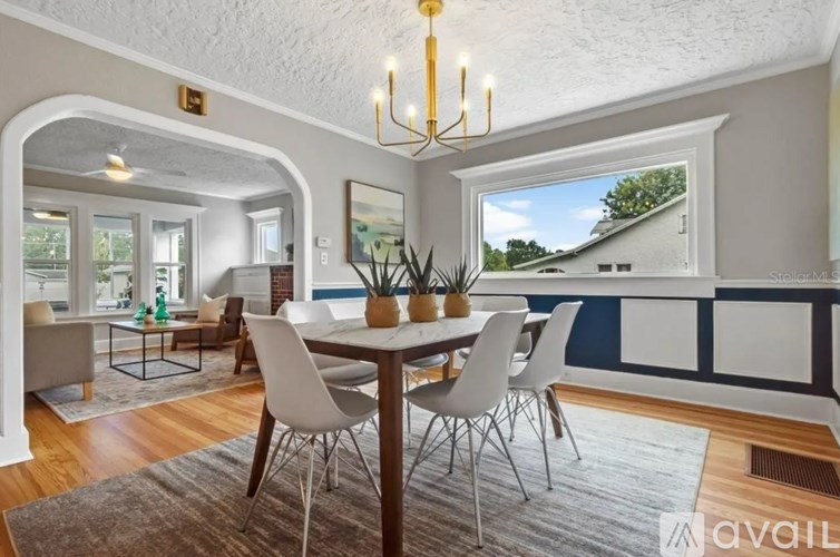A dining room with a table set for four and a view of a house outside the window.