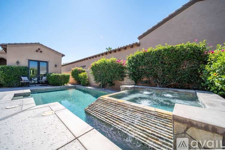 A pool with a hot tub in the middle of a backyard.