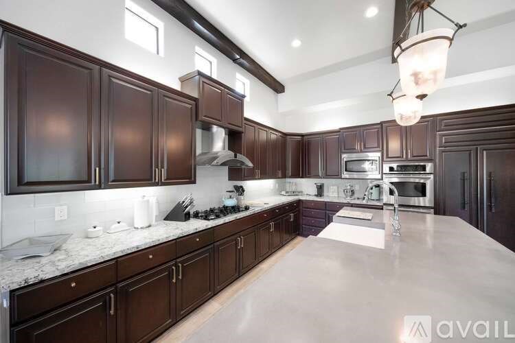 A kitchen with dark brown cabinets and a marble countertop.