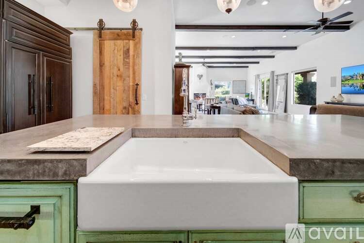 A modern kitchen with a white countertop and green cabinetry.