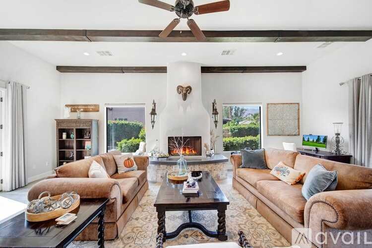 A living room with a fireplace and a ceiling fan.