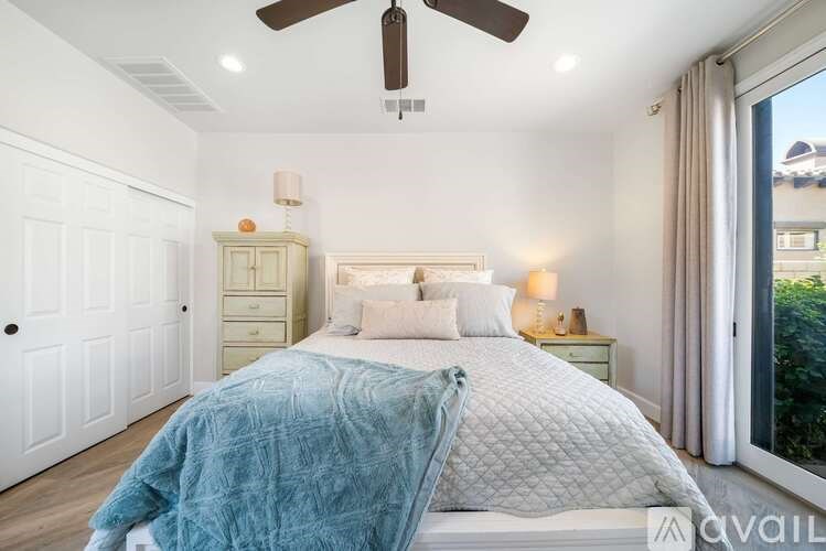 A bedroom with a large bed and a ceiling fan.