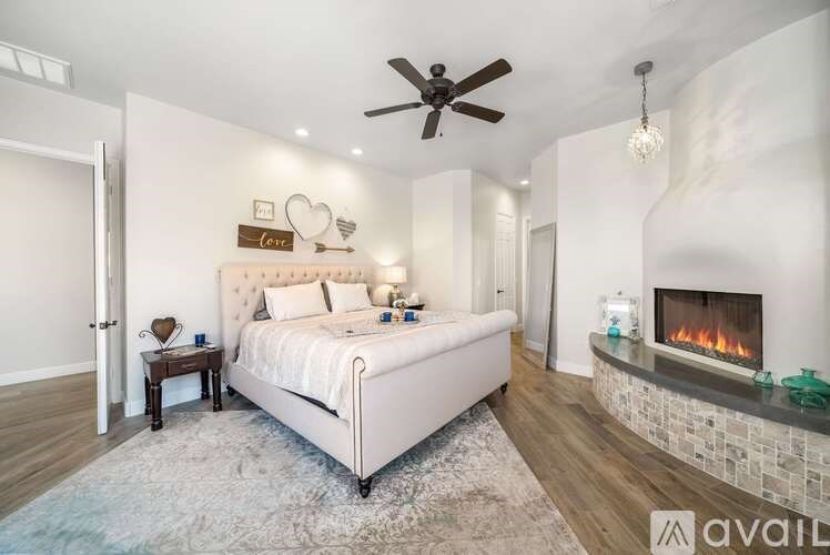 A bedroom with a large bed, a fireplace, and a ceiling fan.
