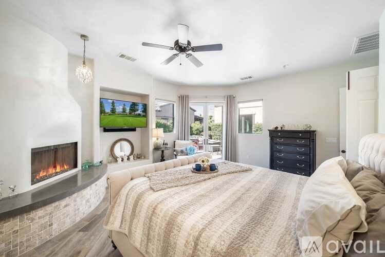 A bedroom with a large bed, a fireplace, and a television on the wall.