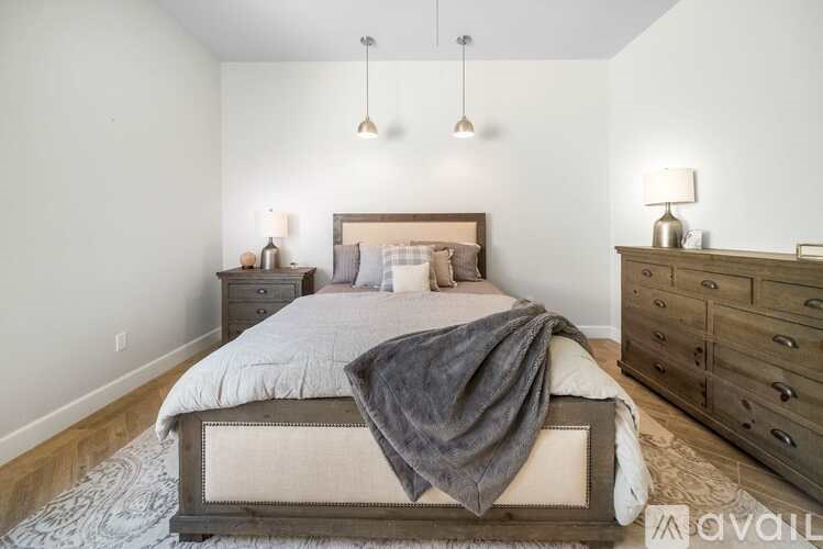 A bedroom with a large bed, a nightstand, and a dresser.