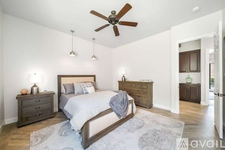 A bedroom with a large bed, a ceiling fan, and a rug on the floor.