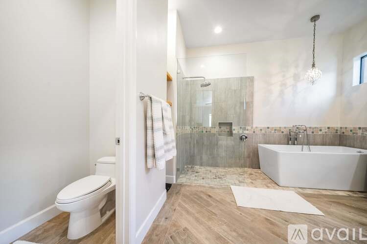 A white toilet is in a bathroom with a walk-in shower.