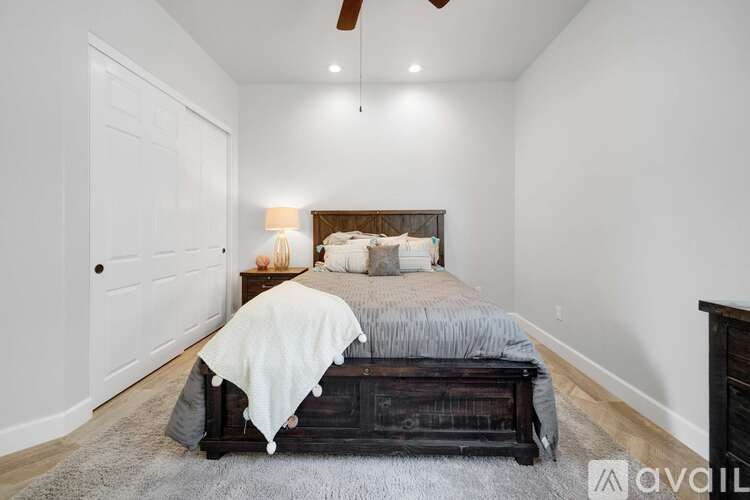 A bedroom with a bed, a lamp, and a ceiling fan.