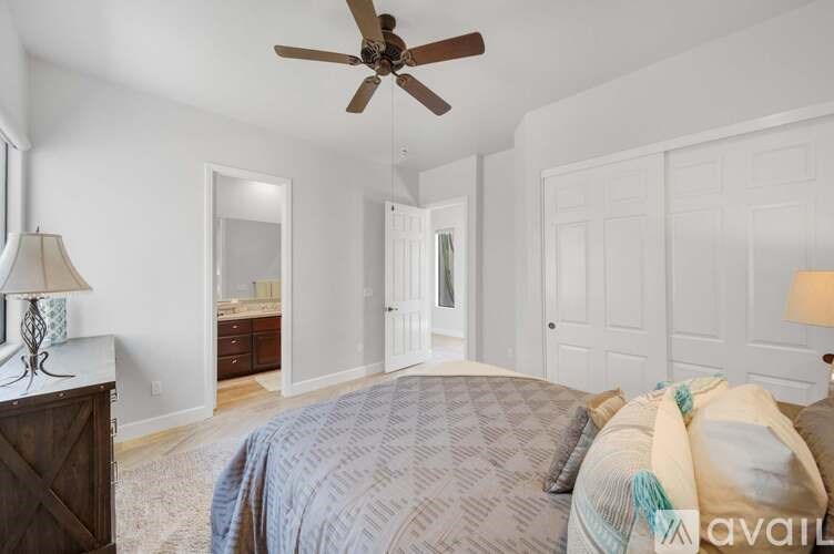 A bedroom with a bed, a ceiling fan, and a dresser with a mirror.