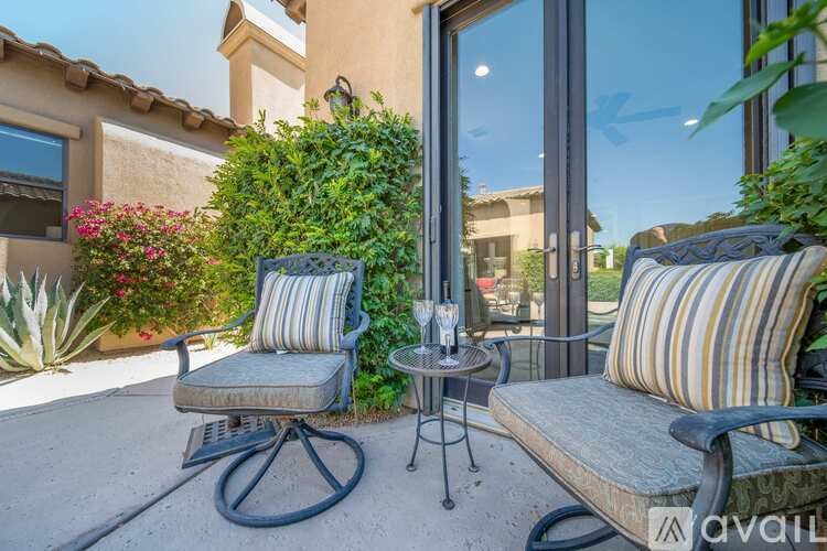 A patio with a chair and a table with a glass on it.