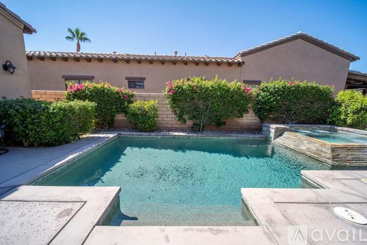 A pool surrounded by a house and greenery.